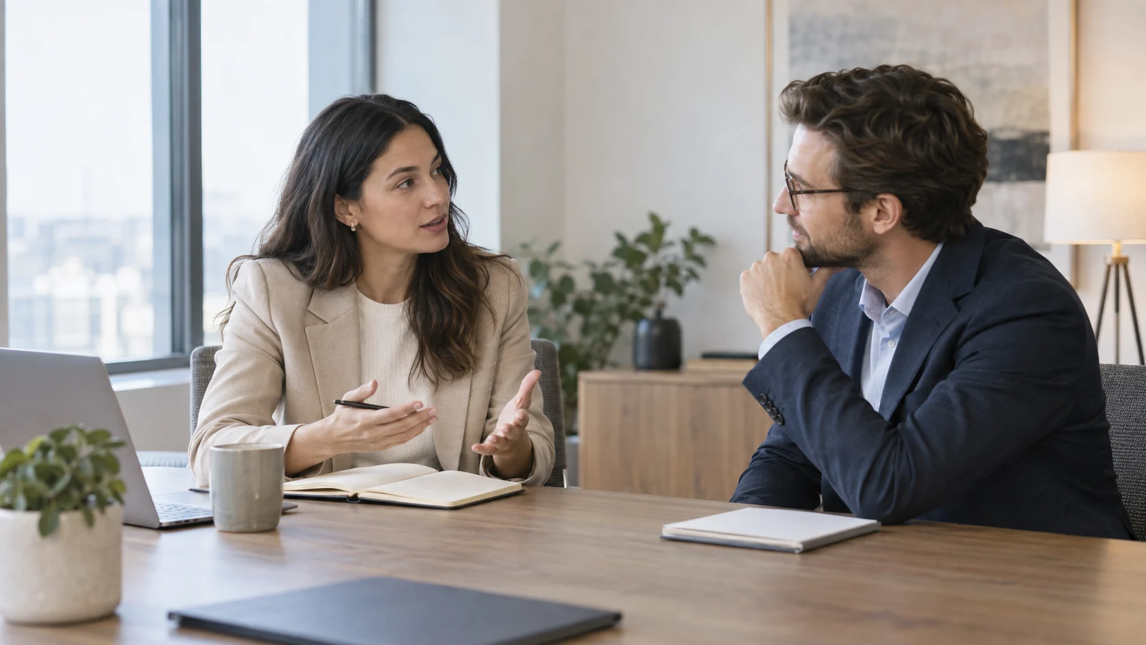 Two professionals having a polite workplace discussion while one asks a question and the other listens attentively.